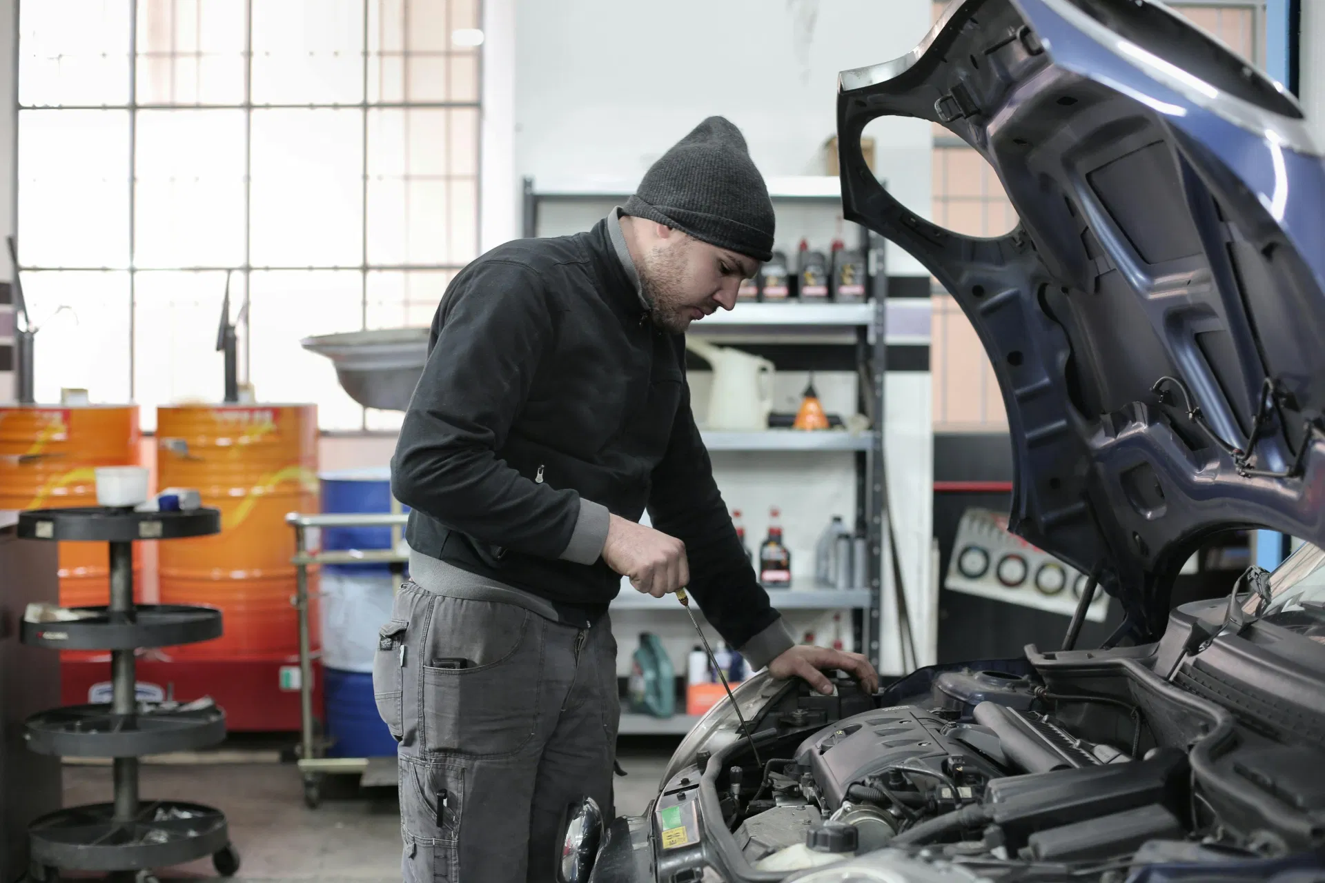 Technician inspecting engine oil using a dipstick under the hood
