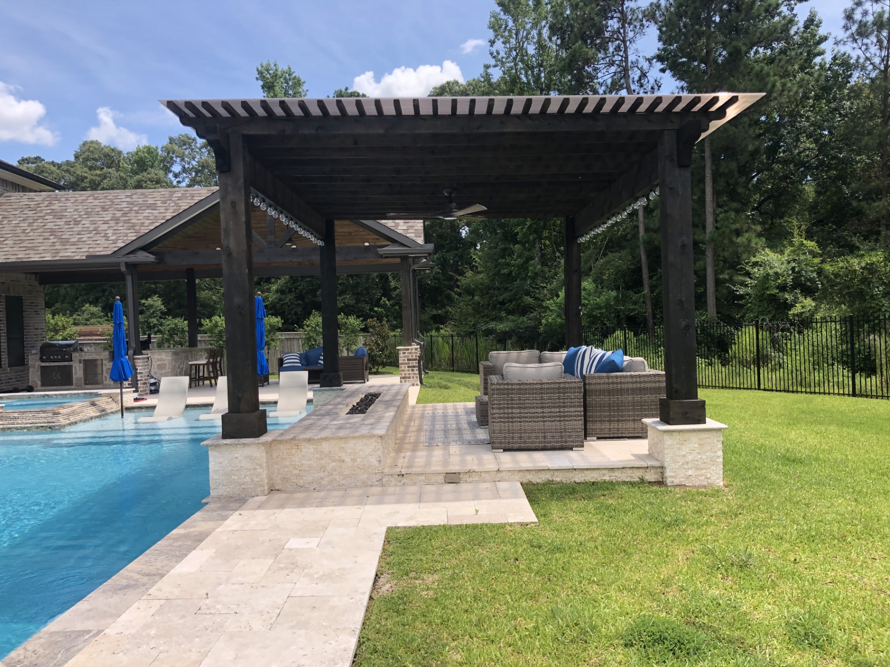 Modern built-in fire pit integrated into luxury pool deck at dusk