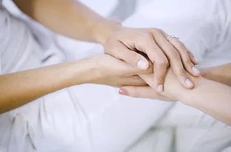 Close-up of two people gently holding hands, symbolizing compassion and understanding.