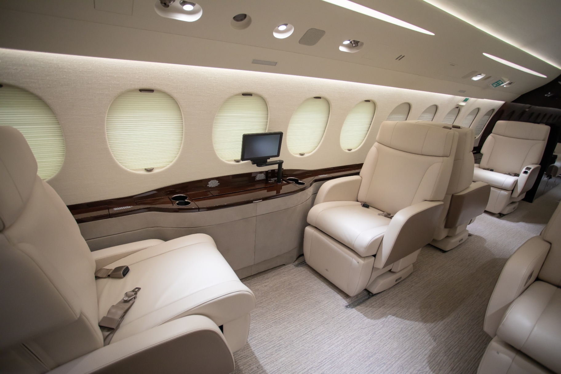 Spacious, modern private jet cabin with individual screens and large windows, reflecting the cabin standards you should expect from a vetted operator
