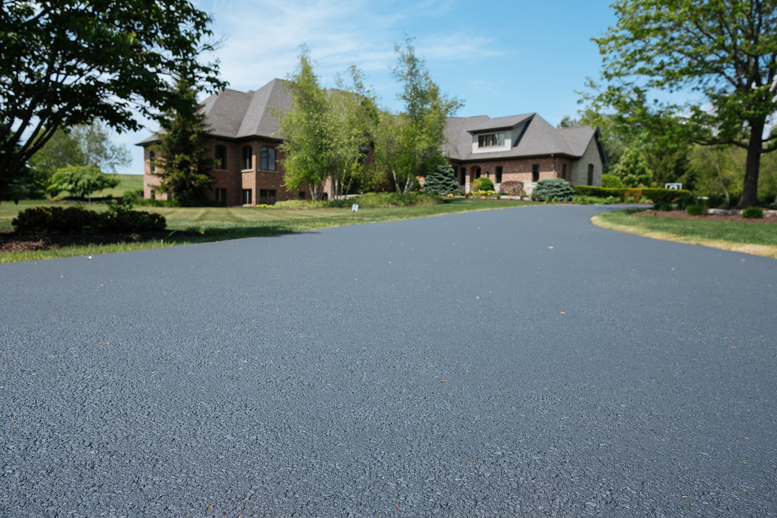 Newly sealcoated residential asphalt driveway with a smooth, uniform finish