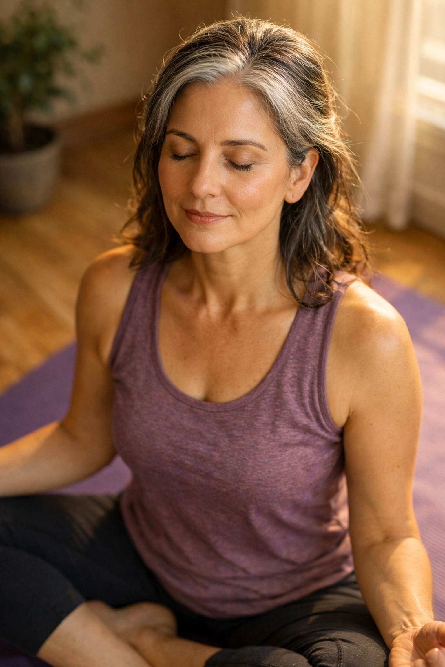Midlife woman practicing seated yoga meditation with peaceful expression showing flow state focus