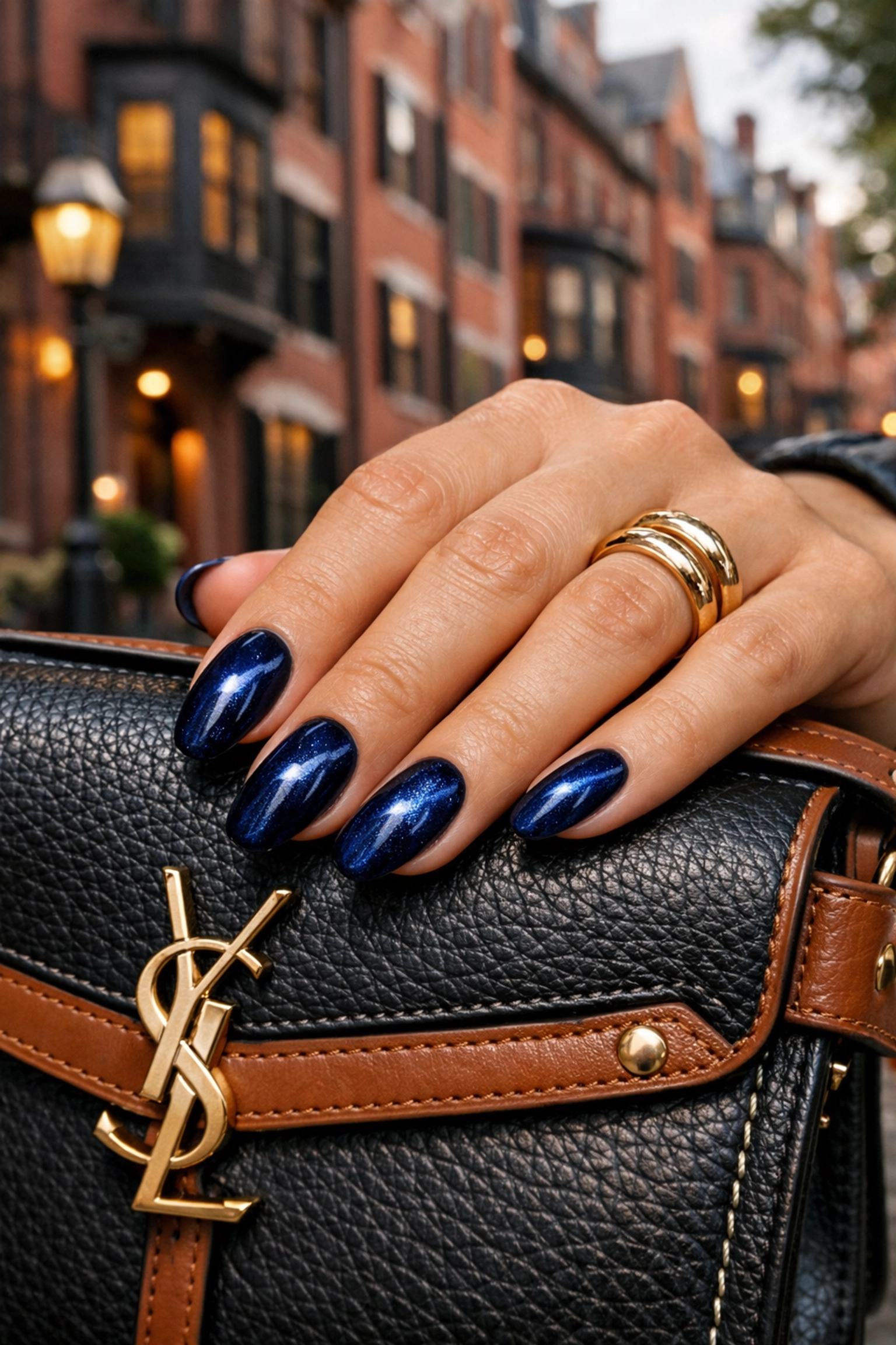 Midnight navy 3D velvet manicure on a hand in front of a classic Boston street scene.