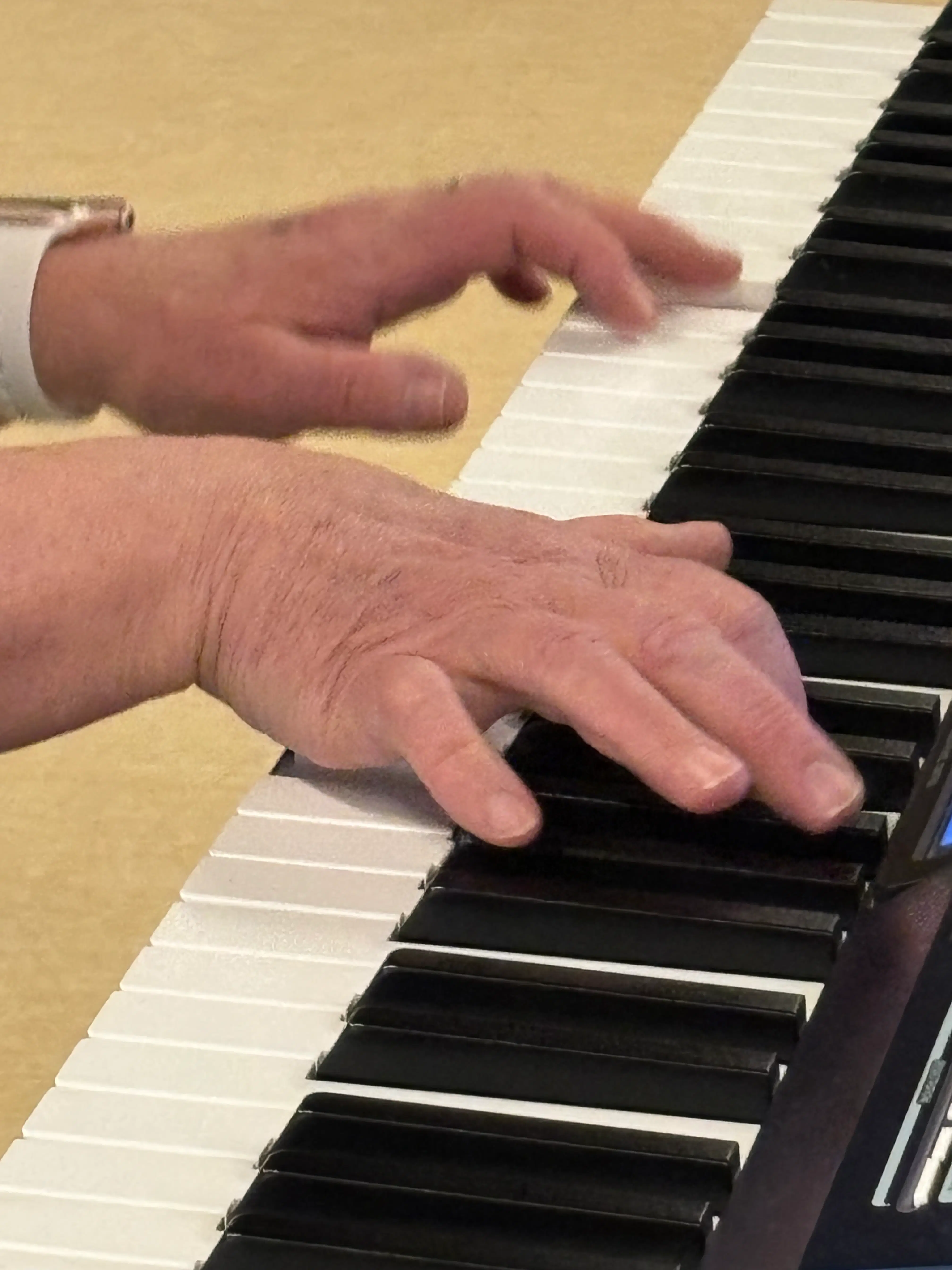 Close-up of adult hands confidently playing chords on a digital piano keyboard