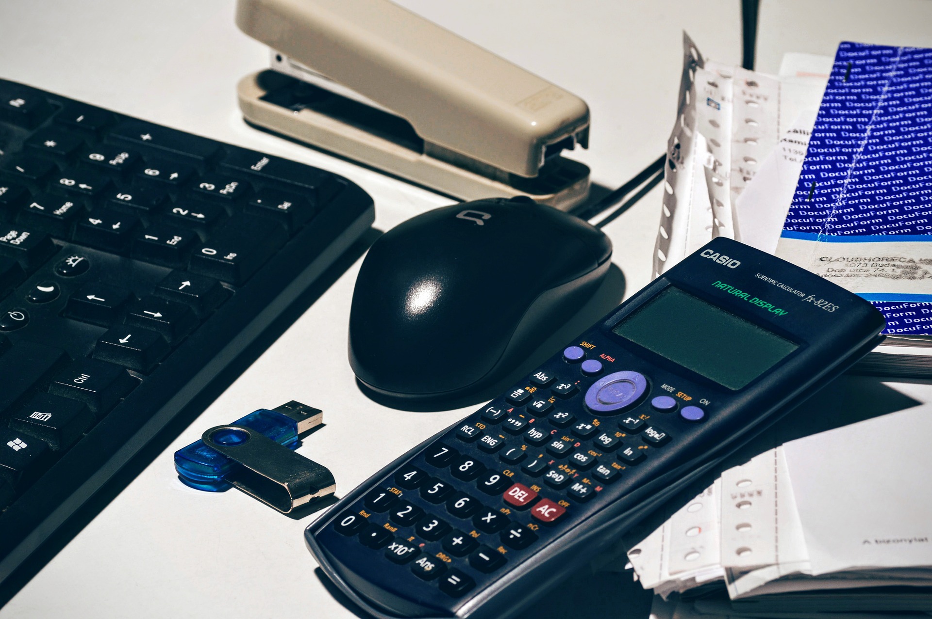 Desk setup with essential bookkeeping tools including a keyboard, mouse, and calculator