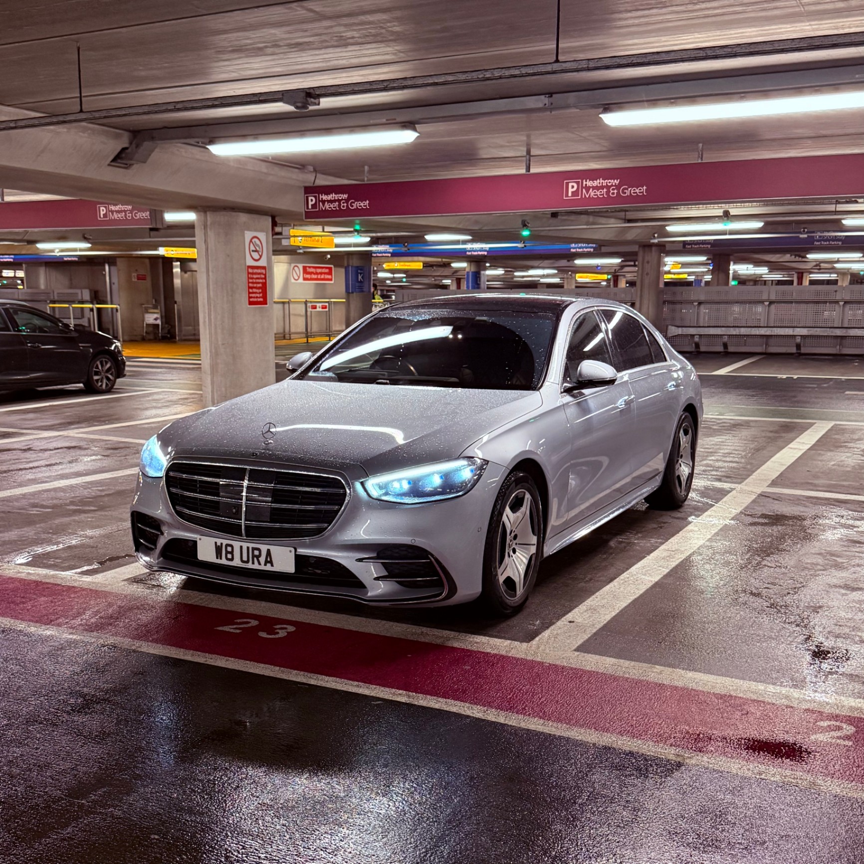 A silver Mercedes-Benz S-Class from Aura Journeys is parked at Heathrow Airport’s Meet & Greet area, ready for a premium chauffeur-driven airport transfer.