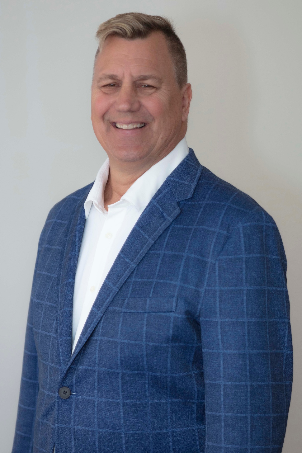 A man in a blue plaid suit jacket and white dress shirt