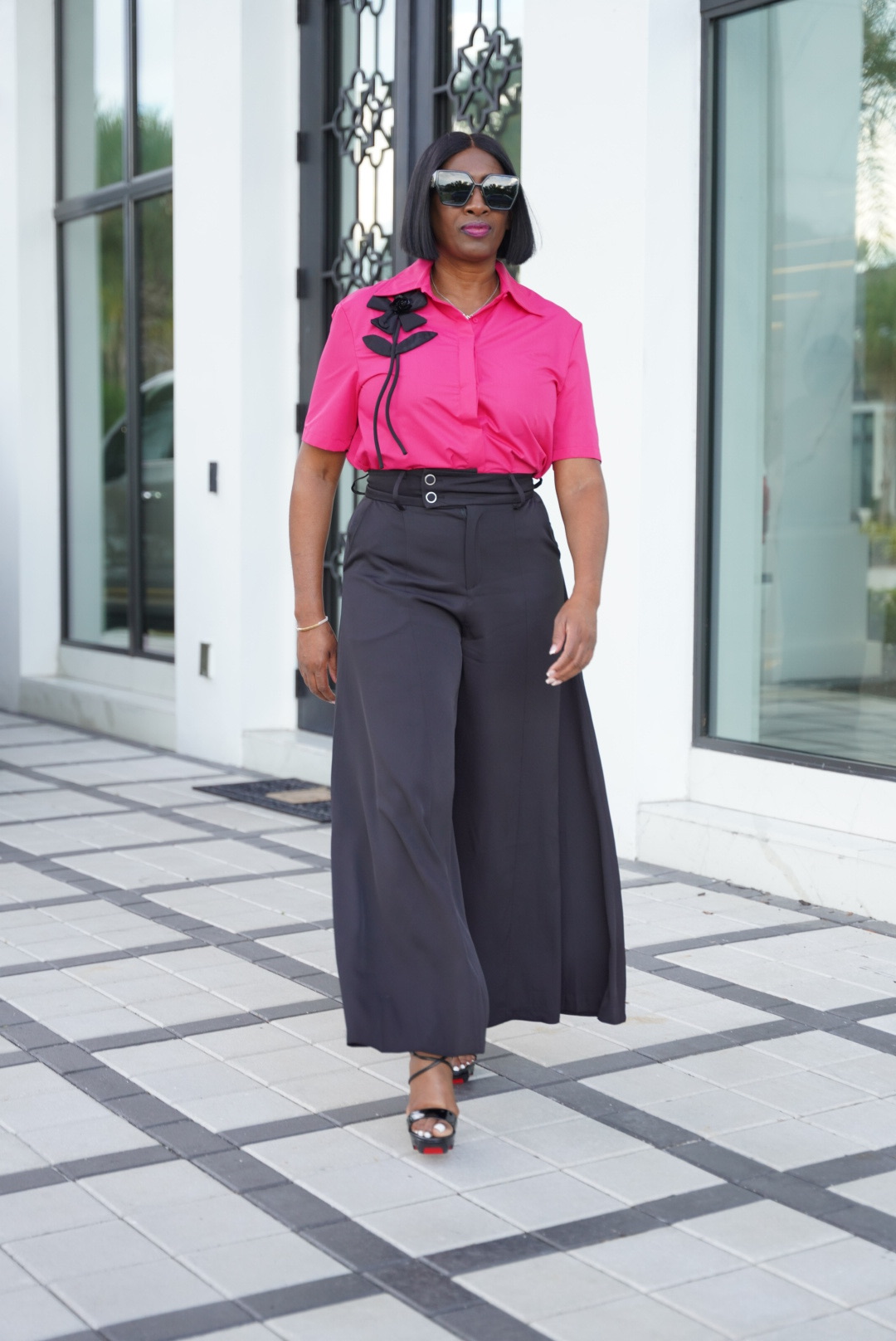 A woman in a pink floral top walking inside Styled4You Boutique.