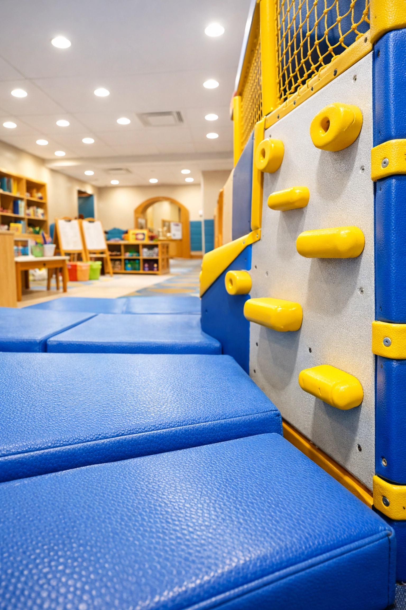 Sanitized indoor play area with blue foam mats and climbing wall in a safe Massachusetts daycare facility.