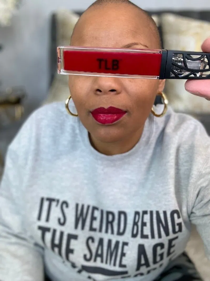 A woman holding a TLB-branded red lip product in an authentic product review shot