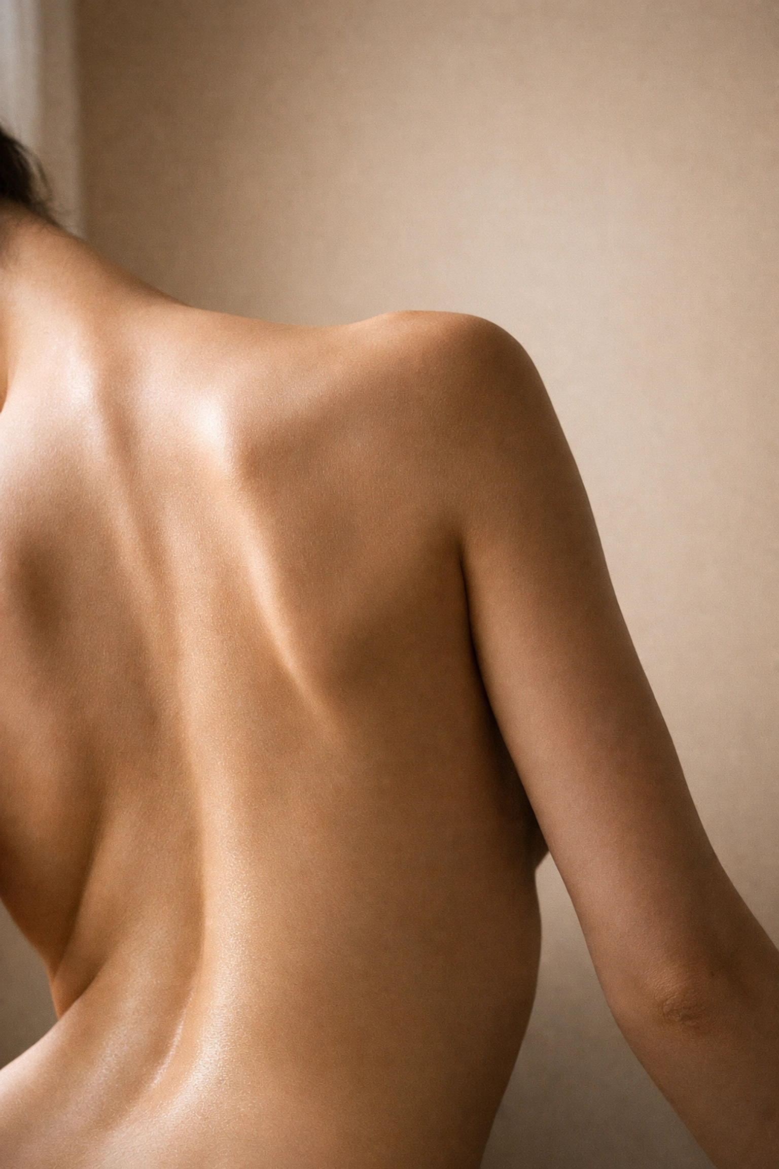 Fine art nude photography showing the architectural curves of a human back with soft natural lighting.
