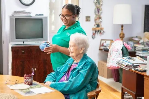 Caregiver assists senior woman at kitchen table