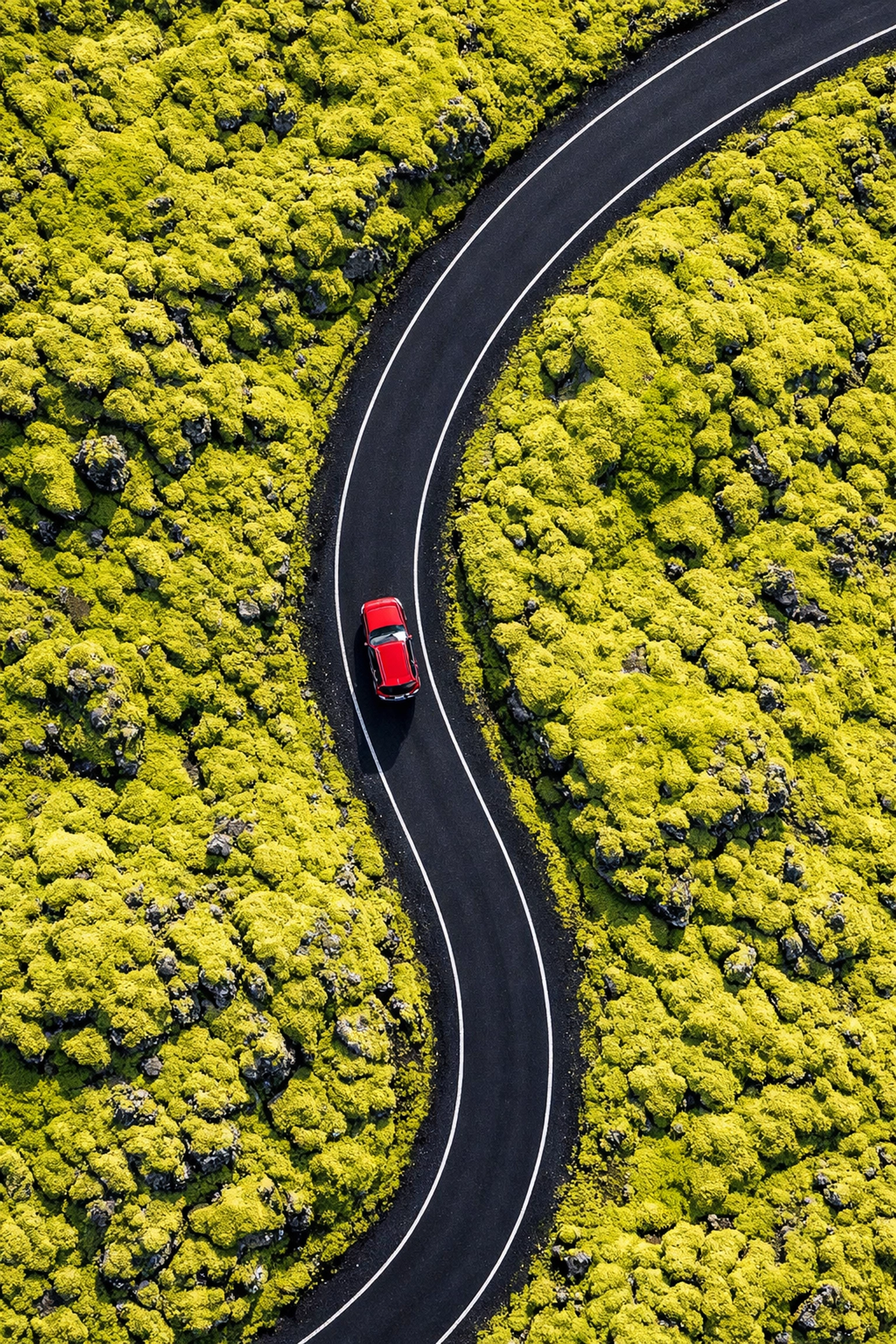 Aerial drone shot of a red car in Iceland's lava fields, highlighting unique perspectives and photography locations.