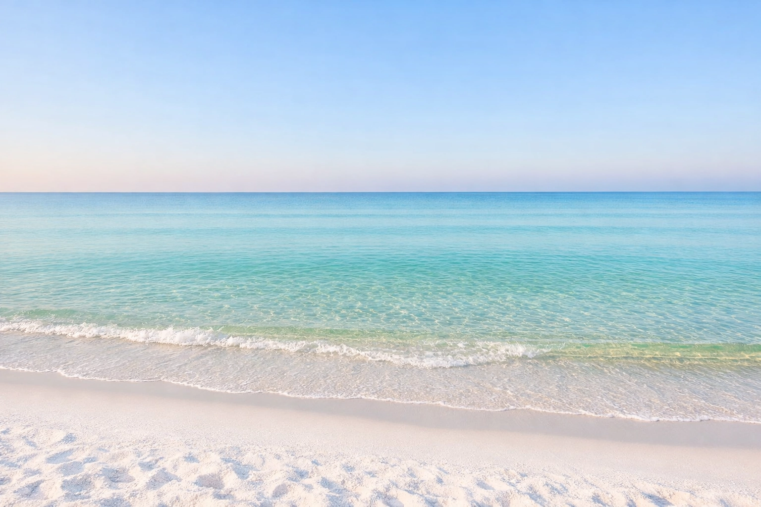 Pristine white sand and emerald green waters of Pensacola beach in the Gulf of Mexico at sunrise.