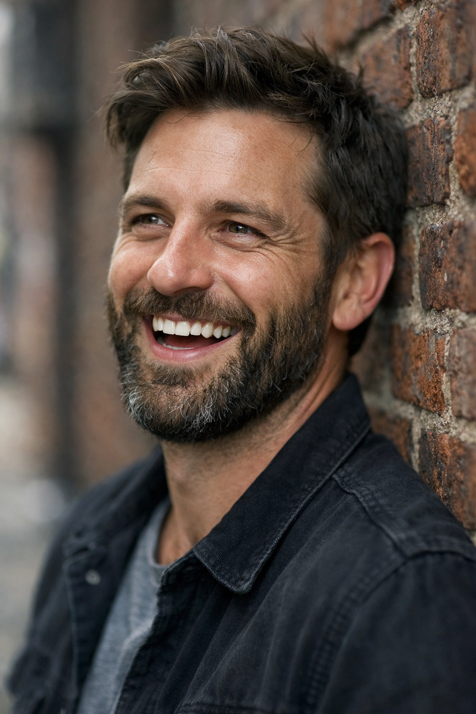 Candid male portrait against a brick wall demonstrating authentic posing and portrait photography techniques.