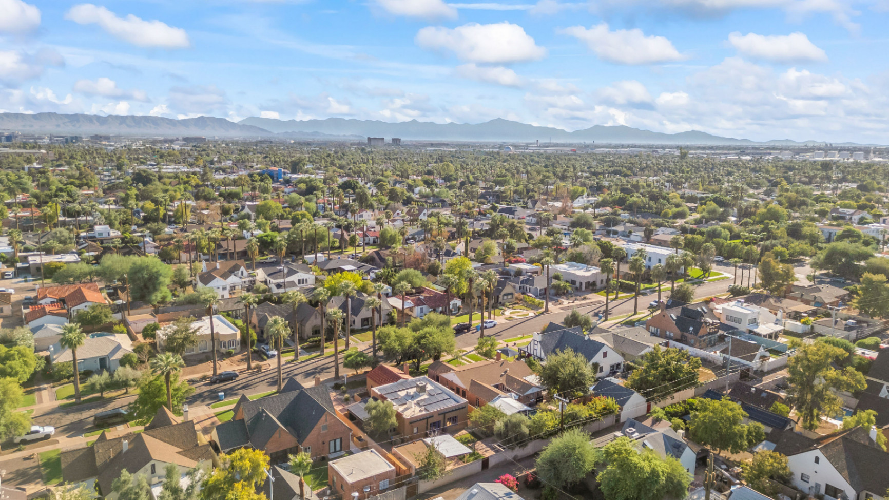 Scenic Suburban Riverfront Neighborhood Aerial view of a vibrant suburban area featuring commercial buildings, parking lots, and residential properties along a picturesque riverfront.