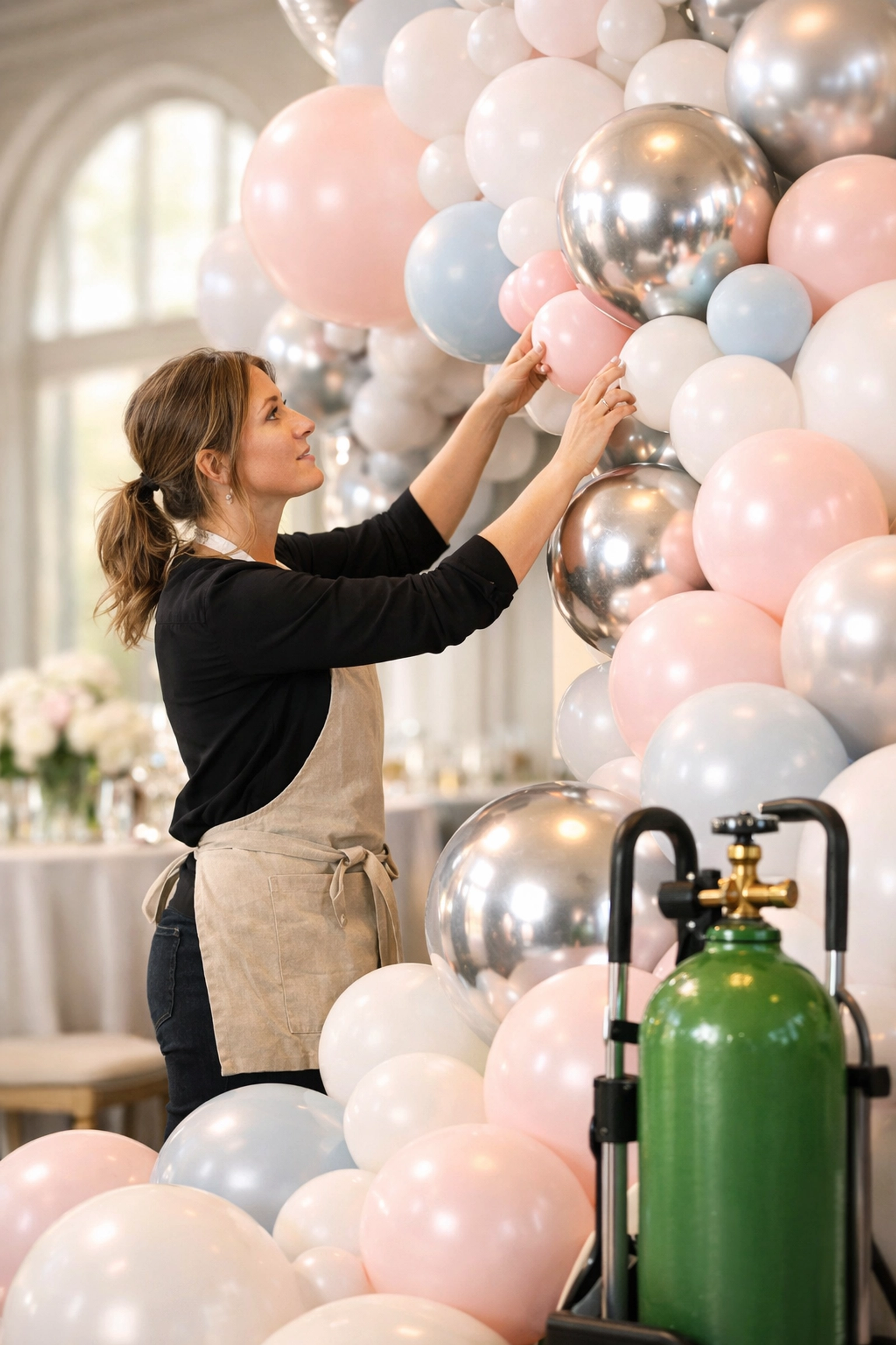 Professional event decorator using a refillable helium gas cylinder for a wedding venue.