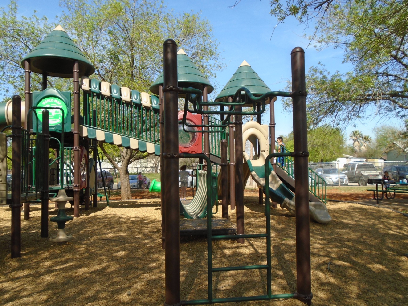 Community playground installation with multi-level structures and shade—durable, inclusive design for all ages