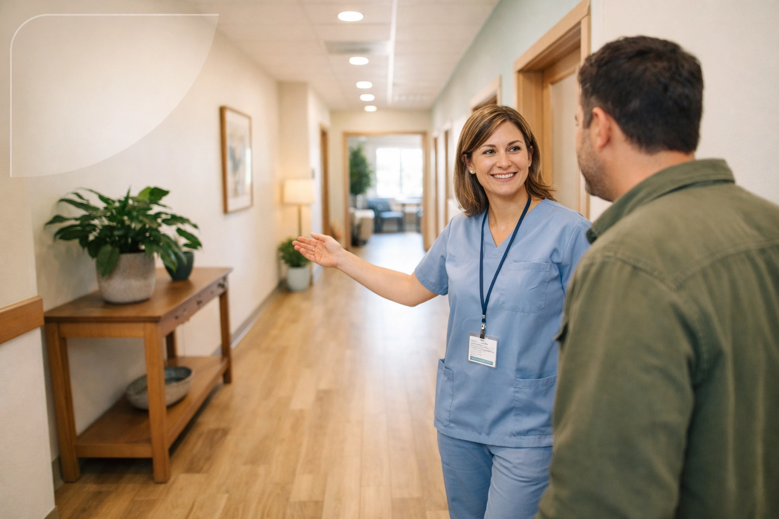 A healthcare professional welcoming a new patient to a clean, bright addiction treatment facility hallway.
