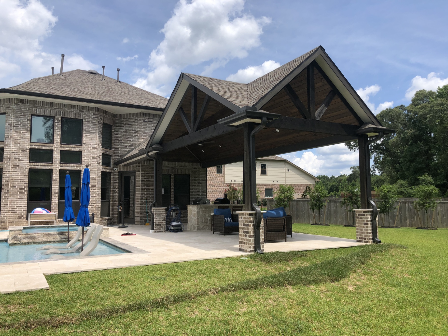 Outdoor kitchen design with bar seating and pool view for luxury poolside entertaining