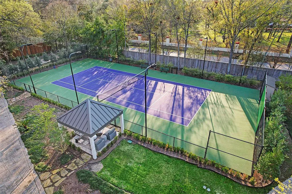 A custom outdoor tennis court in a residential setting featuring professional surfacing and lighting