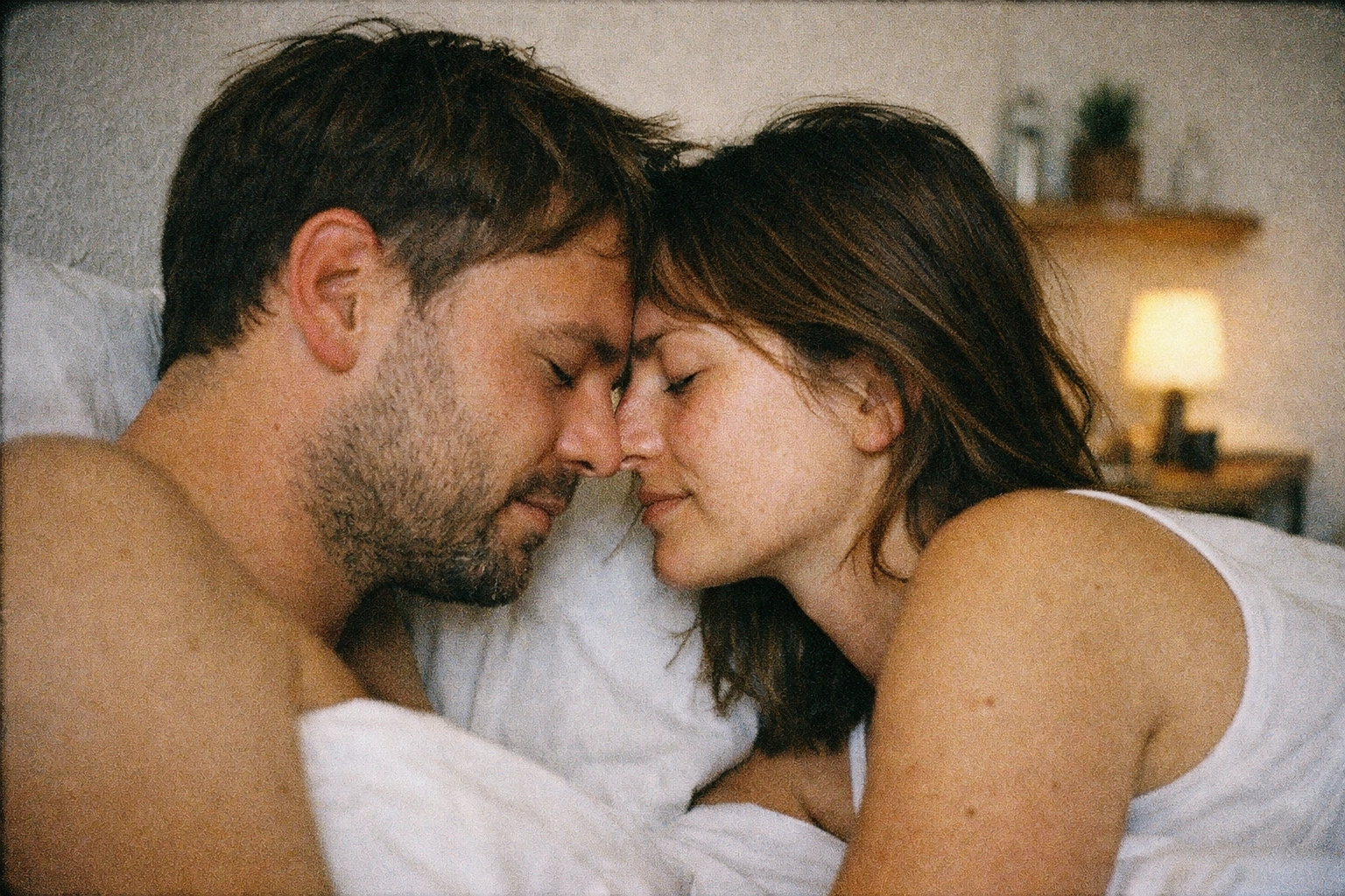 Grainy 35mm close-up of foreheads touching, natural light, early-30s couple, raw vulnerability and longing in bed
