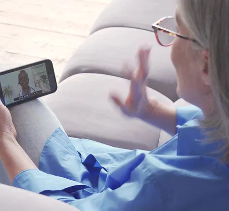 A person sitting comfortably at home, engaging in a telehealth consultation on their phone.
