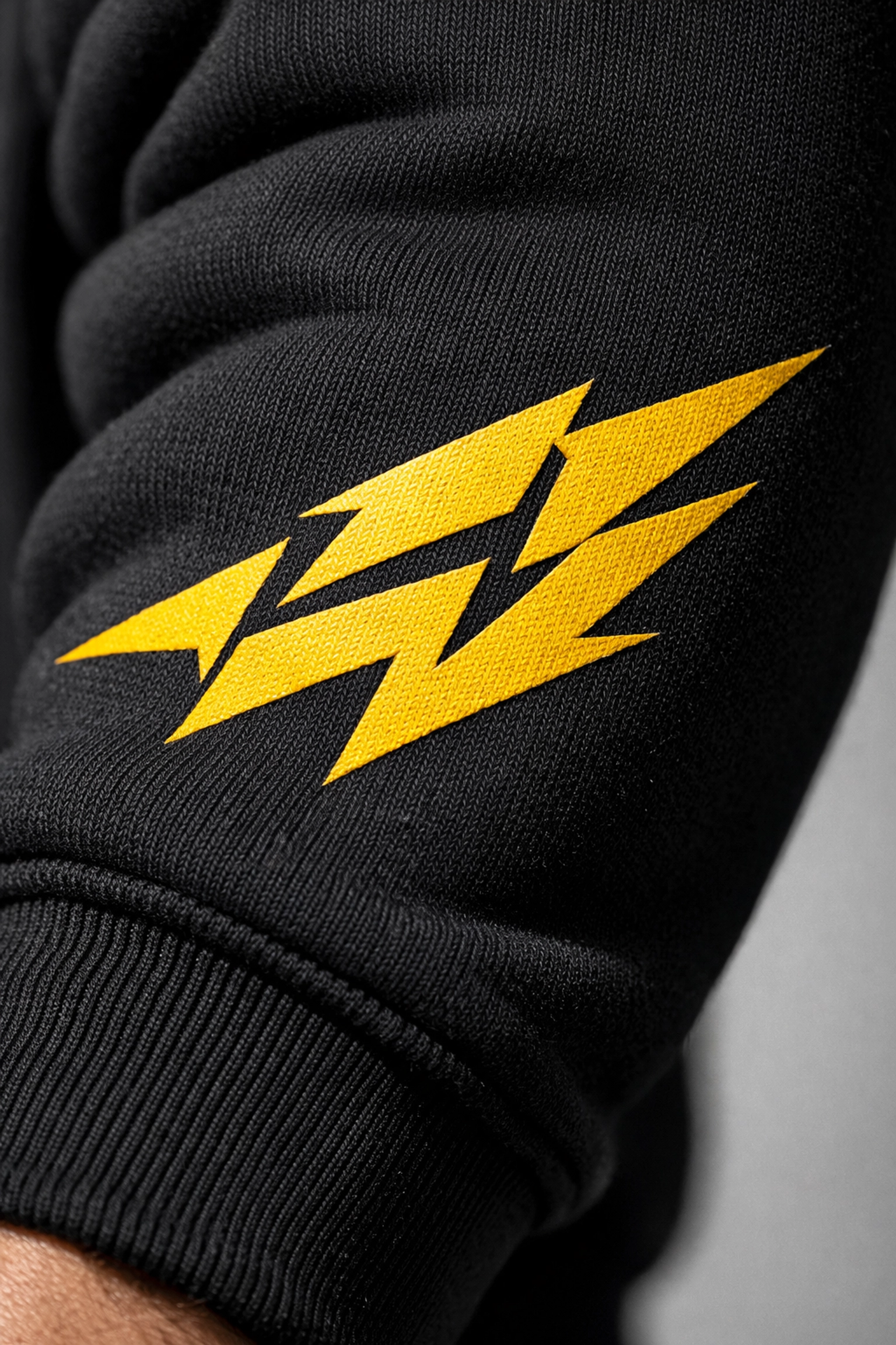 Vibrant yellow screen printing on a black hoodie sleeve showing professional custom apparel quality.