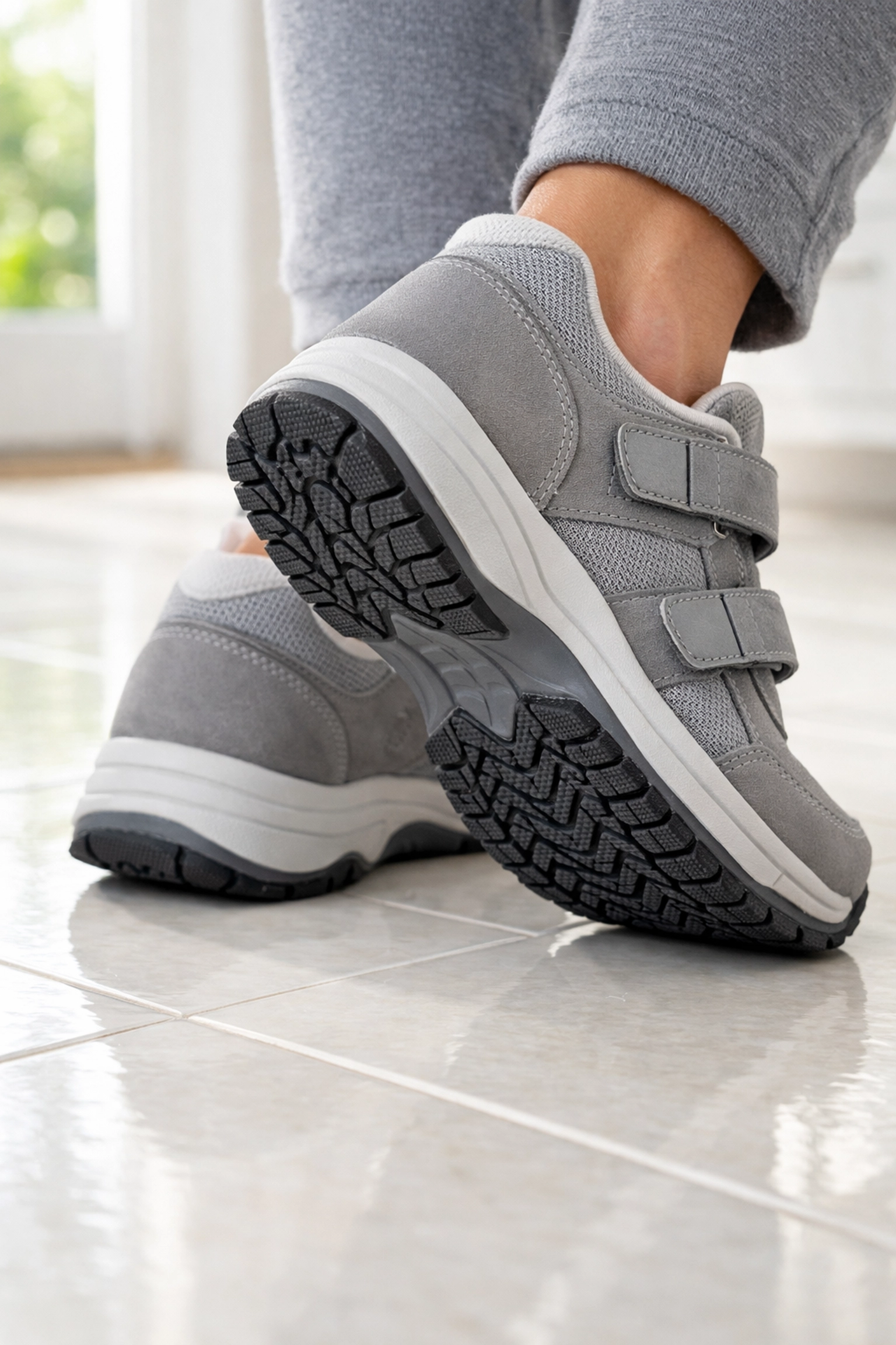 Supportive non-slip shoes for seniors providing traction on a tile floor to prevent tripping at home.