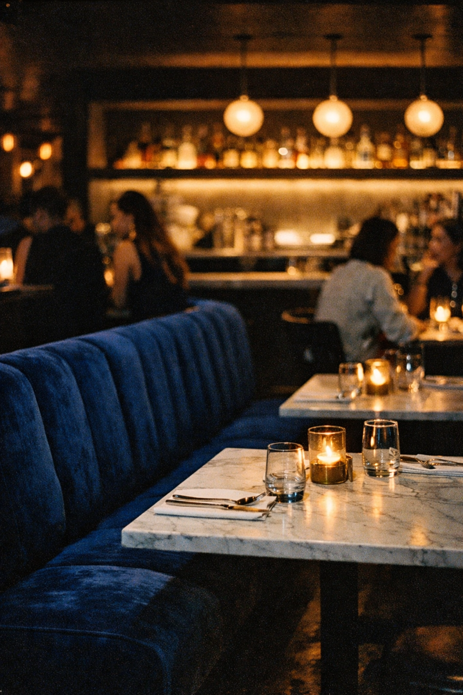 Modern interior of Elena restaurant in Montreal featuring blue velvet banquettes and marble tables.
