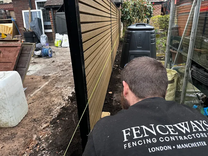 A Fenceways Group Ltd installer aligning a composite fence panel