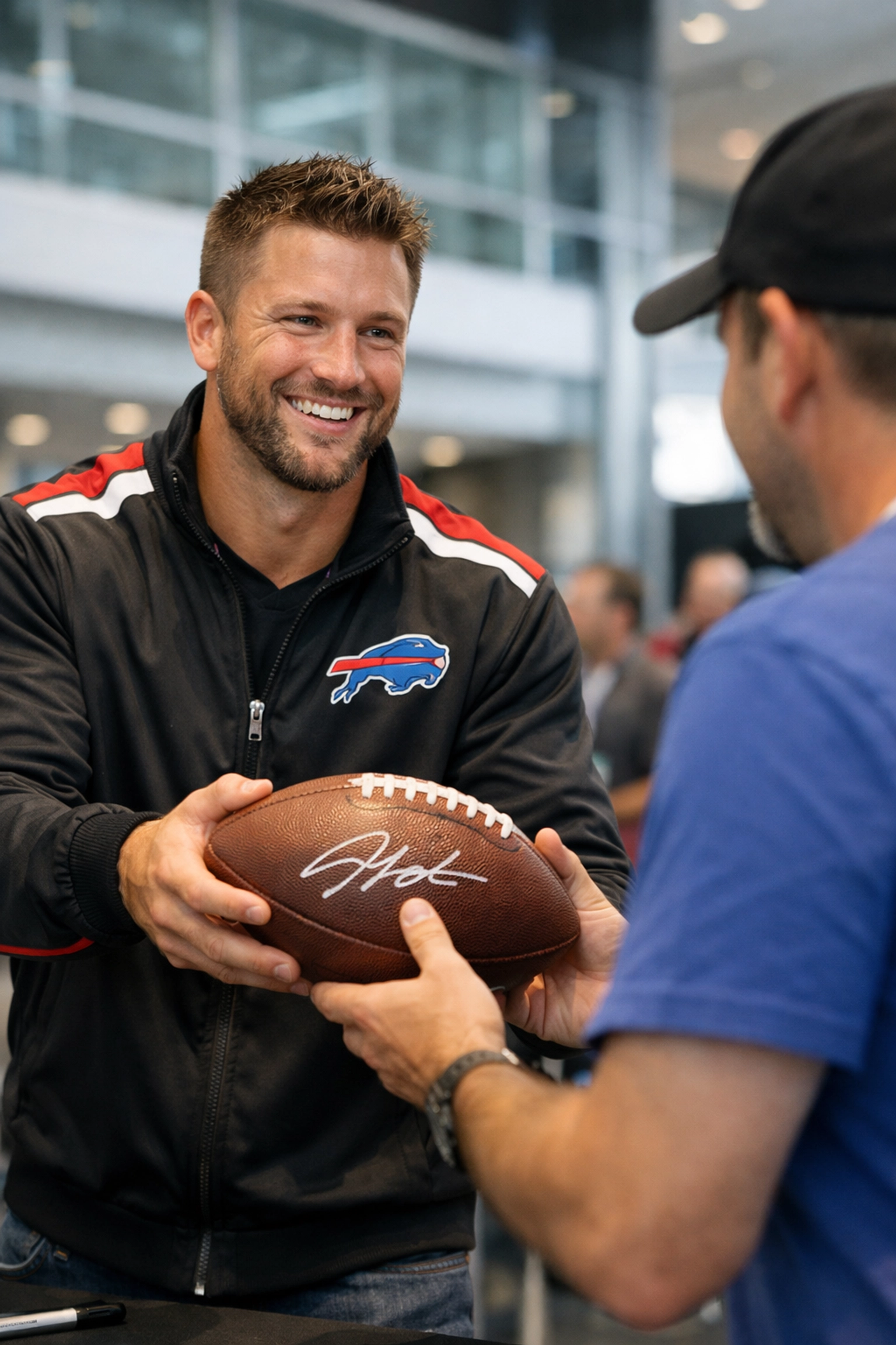 NFL player interacting with an excited fan and handing over a signed football during a Super Bowl event.