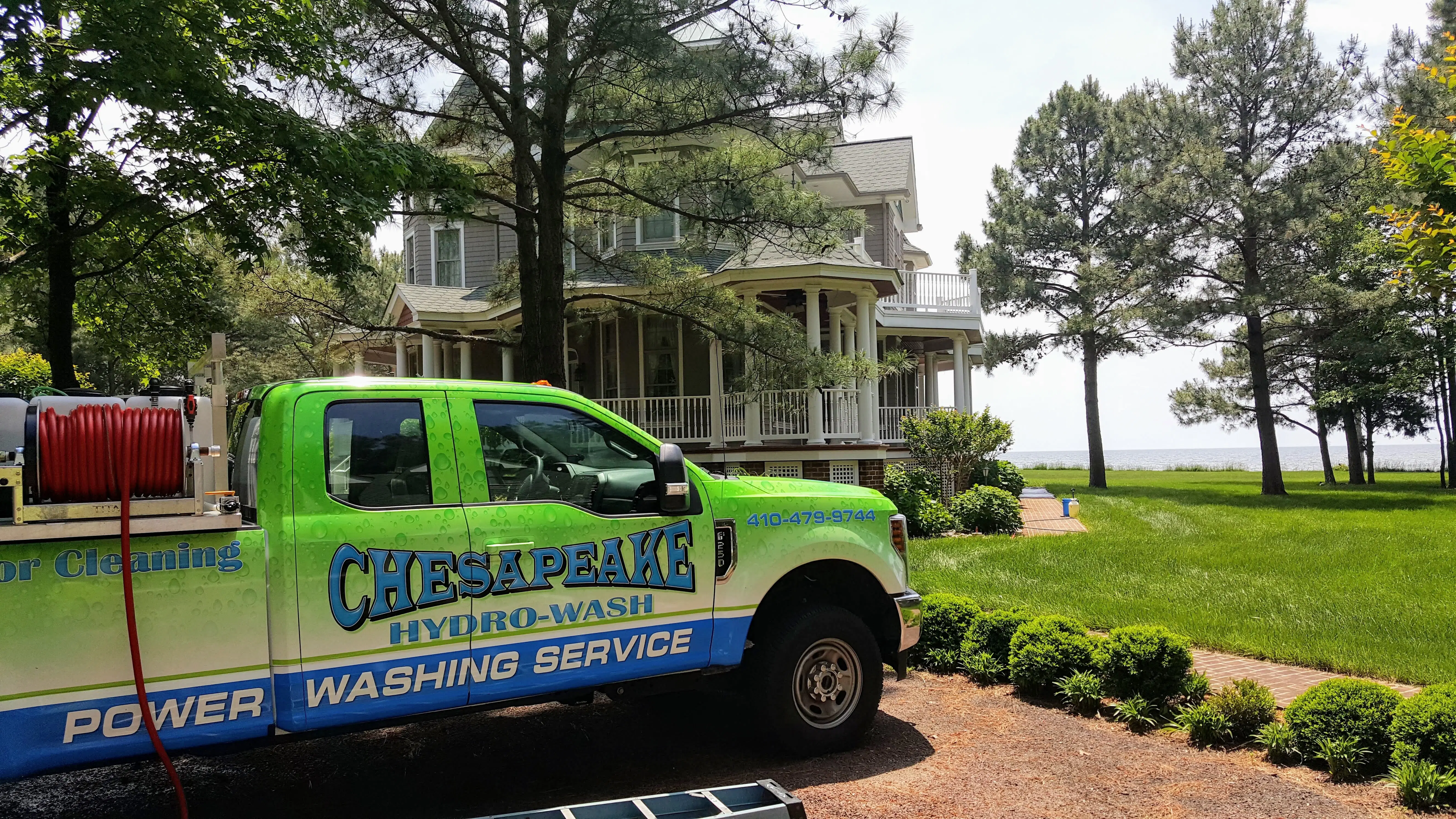 Chesapeake Hydro-Wash service truck parked in front of a well-maintained waterfront home
