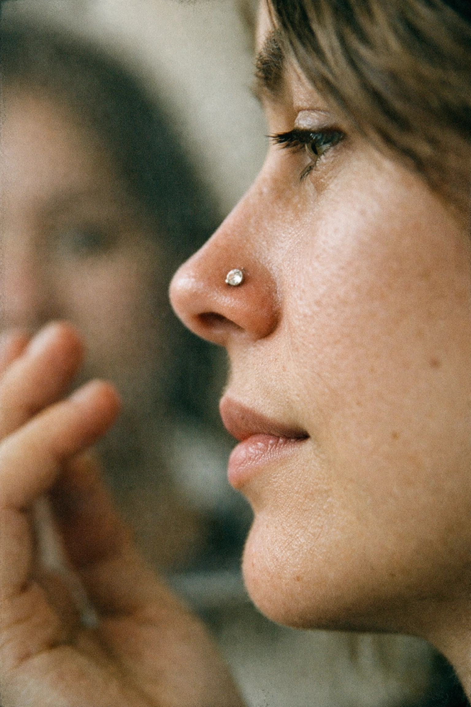 Person with a new titanium nostril piercing following aftercare instructions by not touching the jewelry.