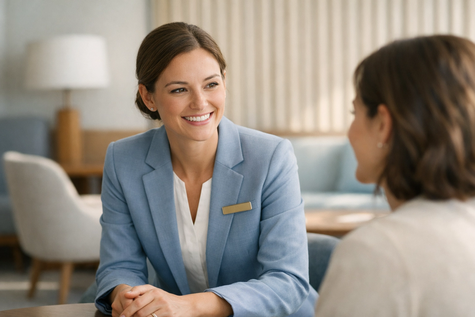 Hotel staff member interacting warmly with a guest in a modern lounge, highlighting human-centric service.