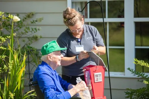 Caregiver assisting senior with bird feeder