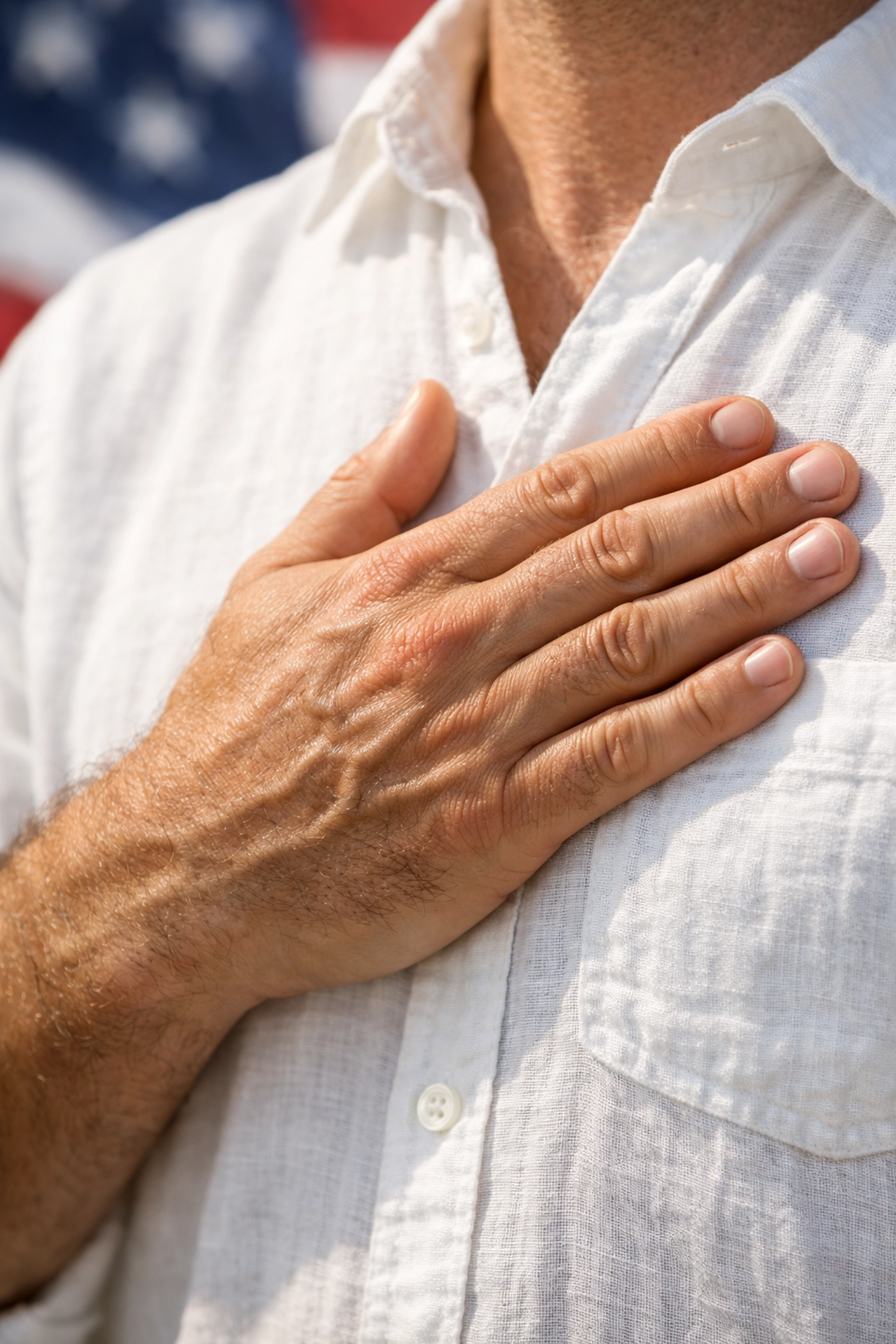 Close-up of the hand-over-the-heart salute against a blurred American flag background for the Pledge of Allegiance.