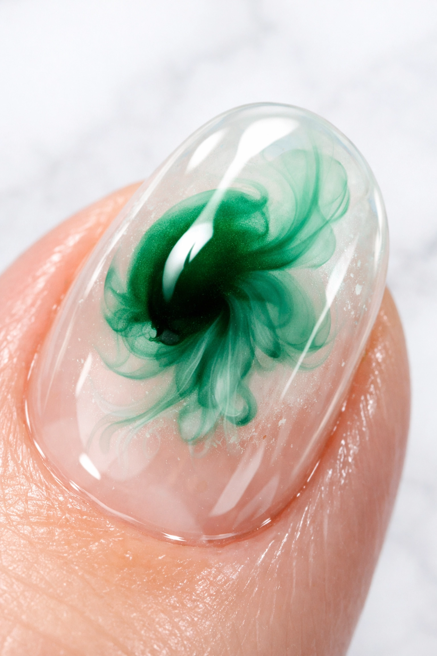 Close-up of emerald green Japanese blooming gel creating a fluid watercolor effect on a manicured nail.