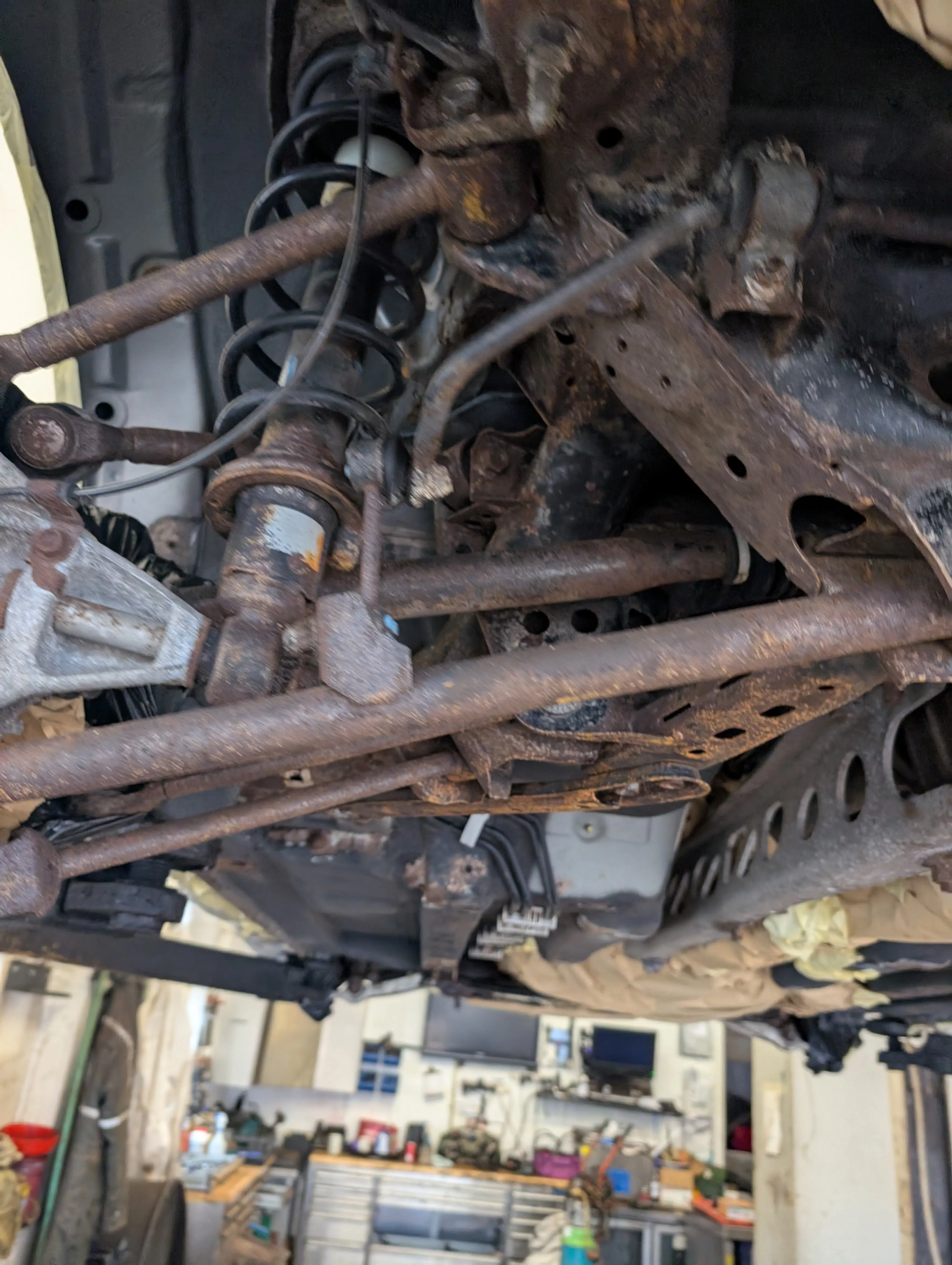 Severe surface rust on vehicle underbody components including suspension arms and chassis mounts