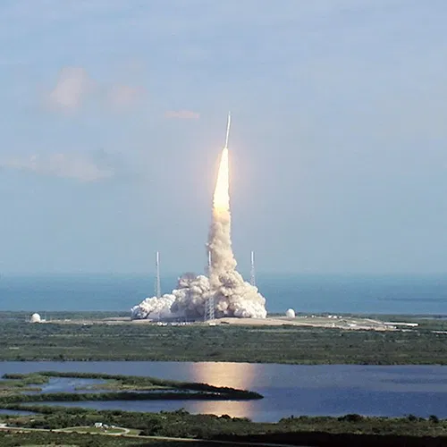 A powerful rocket lifts off from Cape Canaveral, leaving a bright plume in the sky above the Indian River Lagoon.
