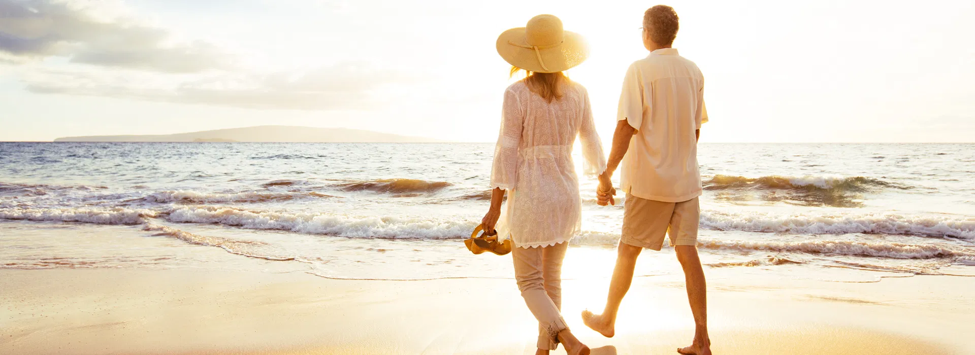 older-couple-walking-beach-sunset-pain-relief.webp