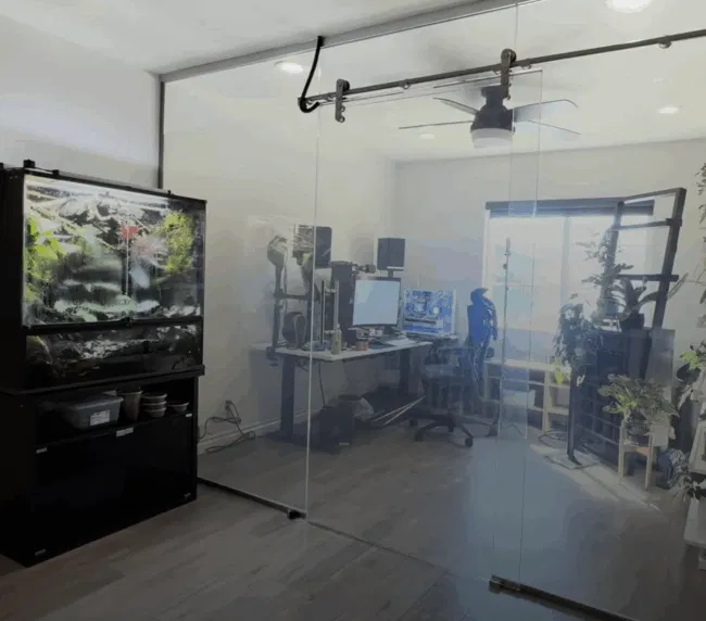 Home office with large frameless smart glass sliding partition installed as a room divider