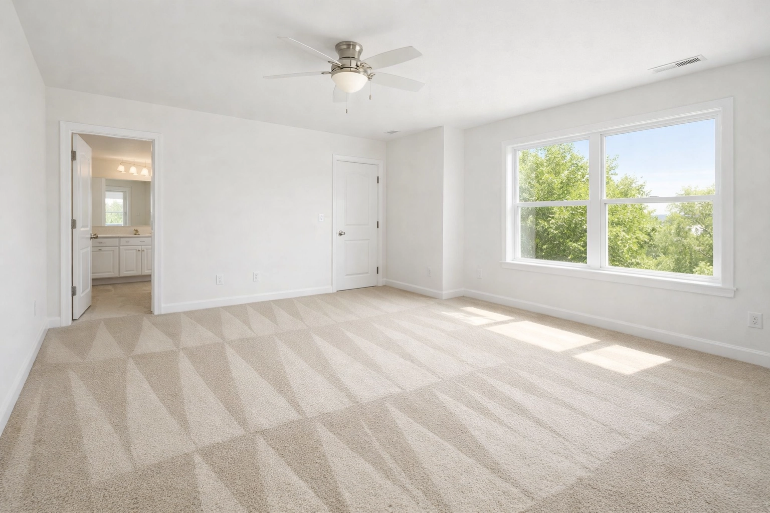 Empty rent-ready master suite with professionally vacuumed carpets and natural light after move out cleaning.