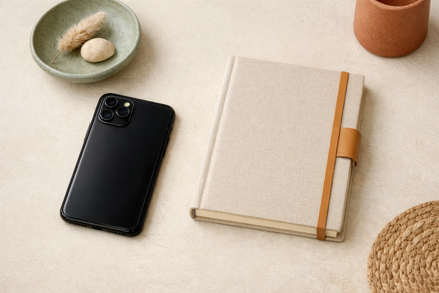 Smartphone face-down beside a notebook on a cream desk with sage and terracotta accents for a Business Boho social media boundary visual
