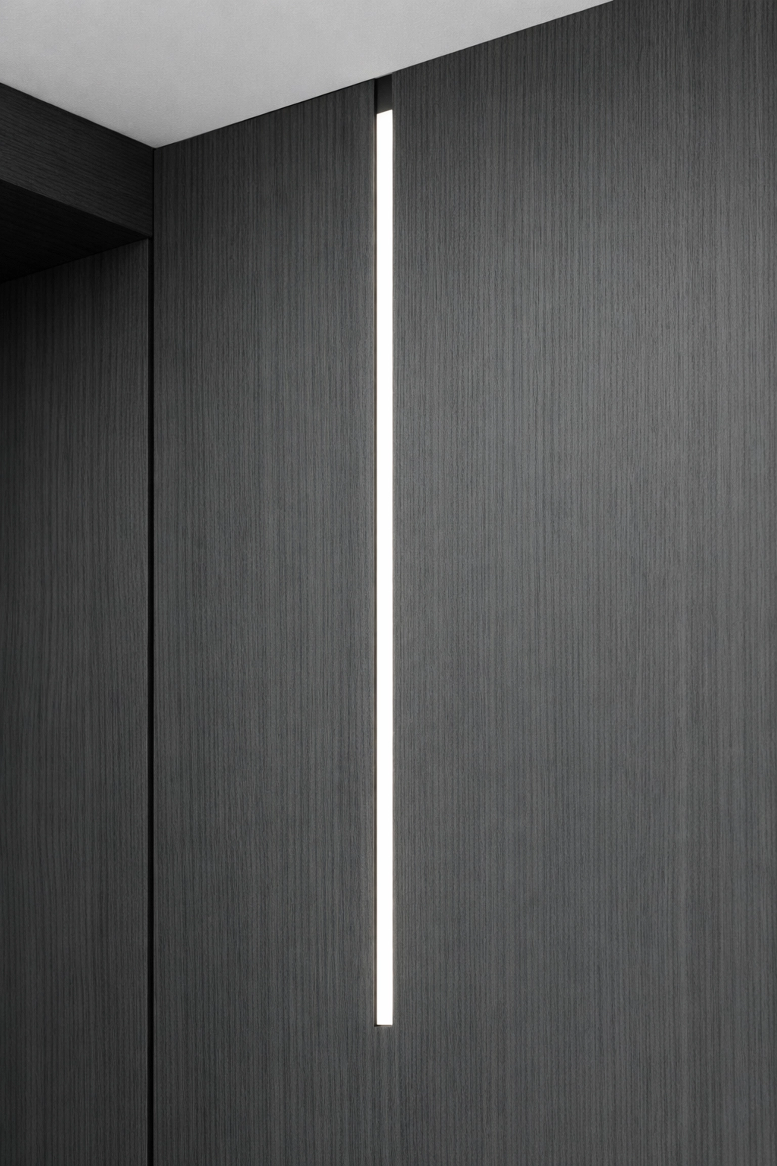 Seamless vertical linear LED lighting integrated into a custom dark wood wardrobe gable.