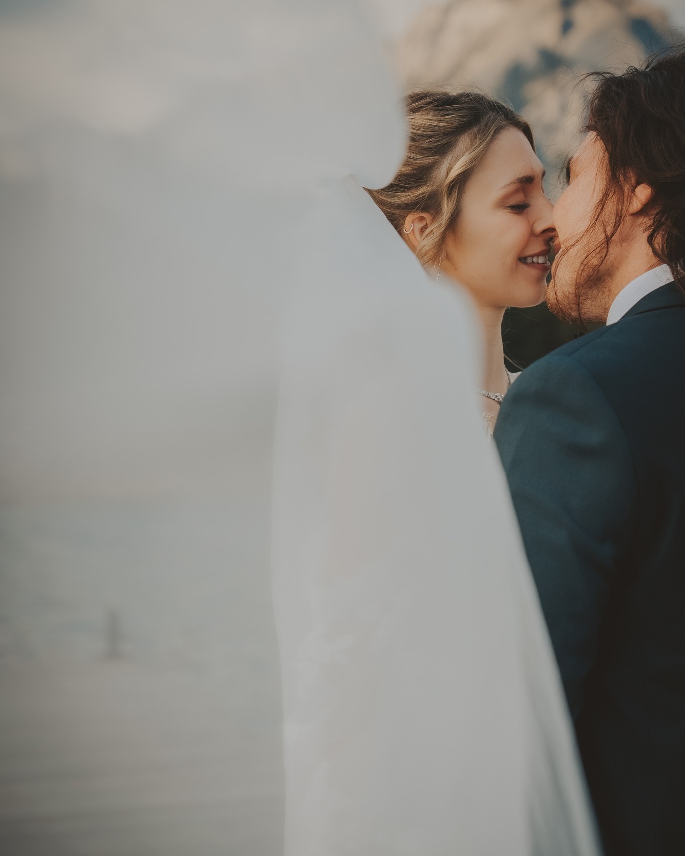 A couple shares an intimate moment during their elopement ceremony, with the Canadian Rockies blurred in the background.