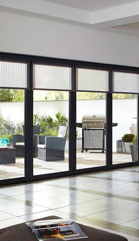 Floor-to-ceiling aluminium bifold doors seamlessly connect a tiled interior with an outdoor patio.