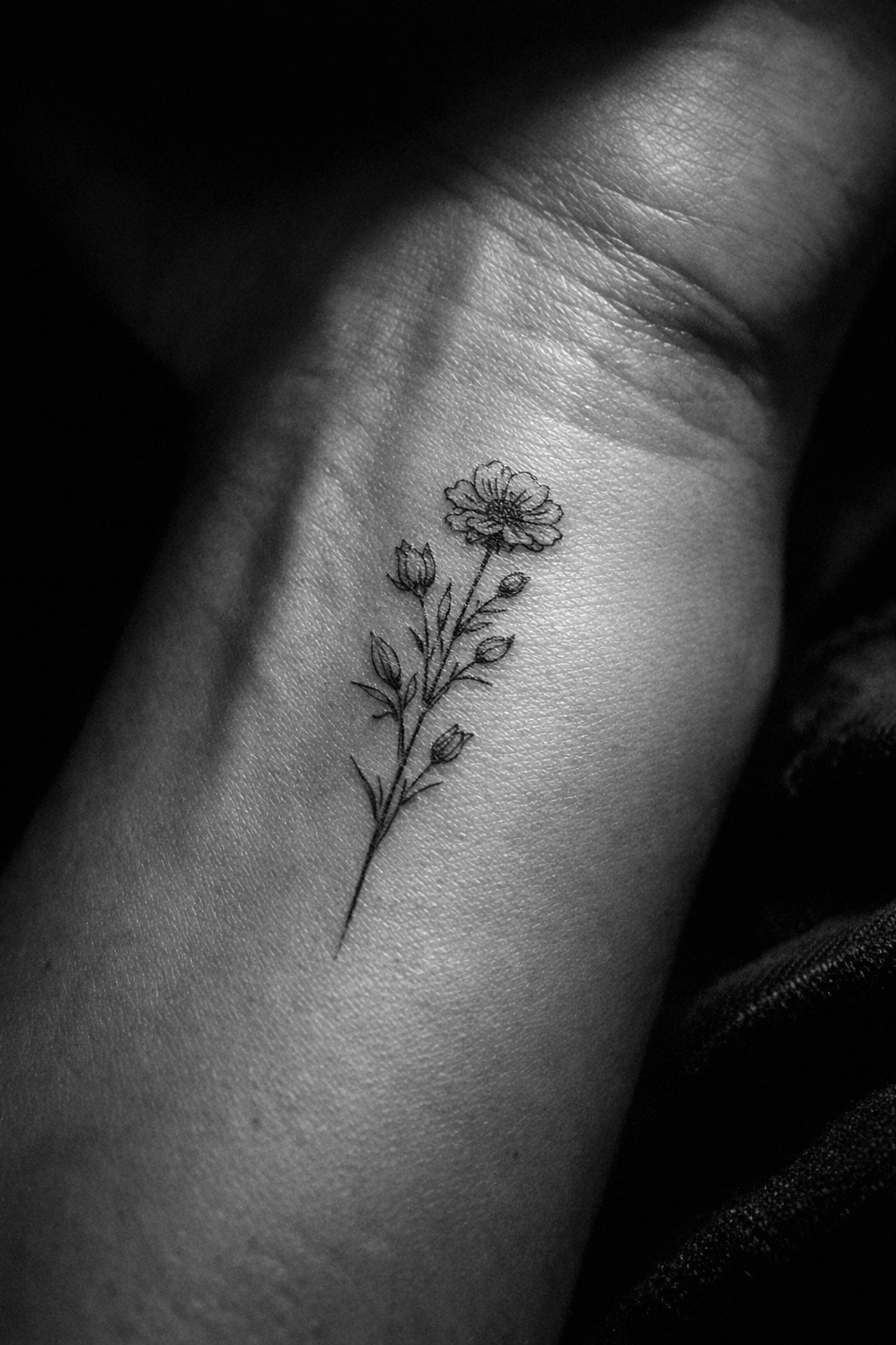 Detailed fine line wildflower tattoo on a wrist, showcasing delicate botanical ink in Woolwich SE2.