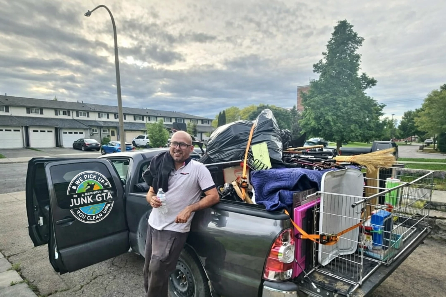 Junk removal crew member standing beside a pickup truck loaded with various junk items