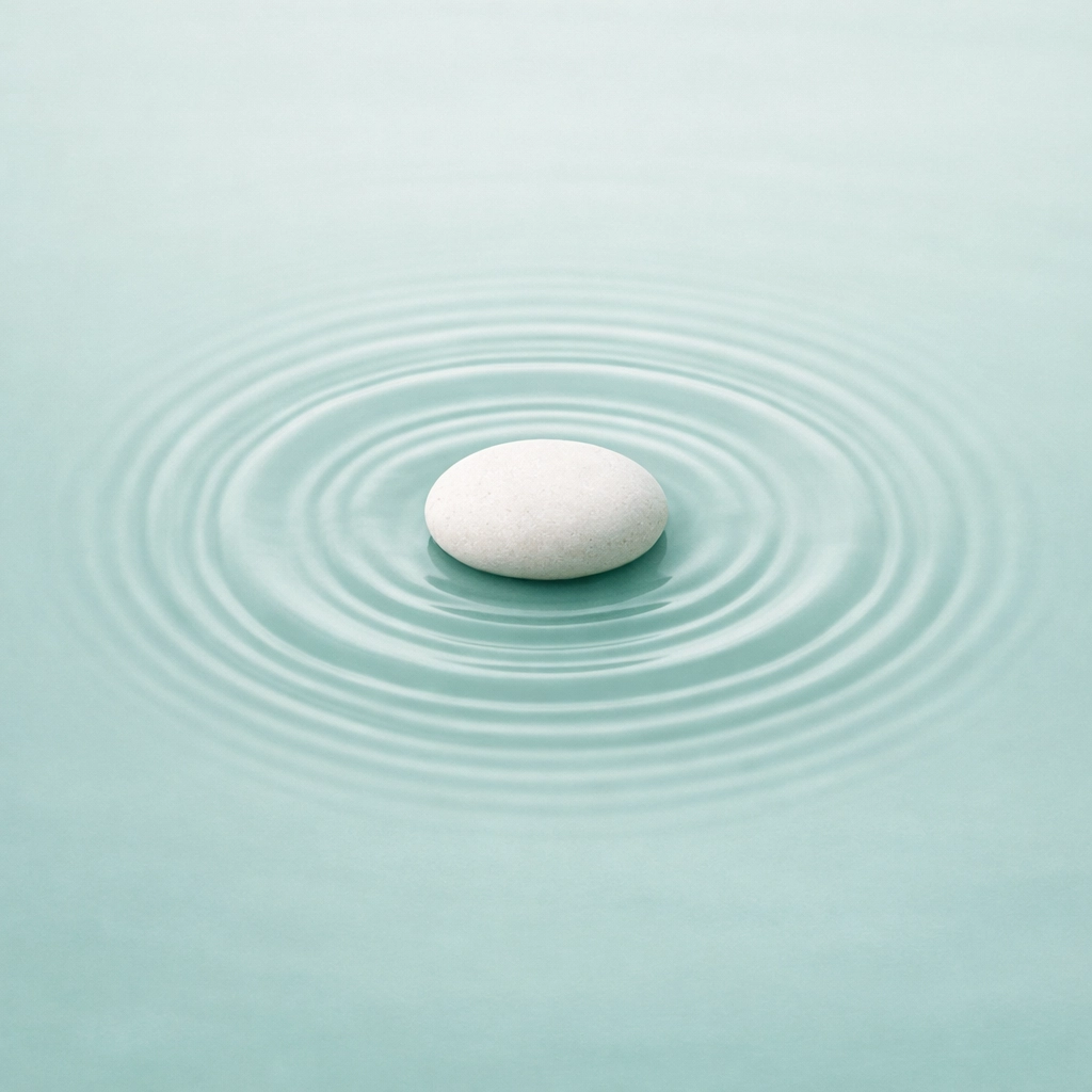 Smooth white stone in soft water ripples, symbolizing grounded resilience and empathetic leadership.